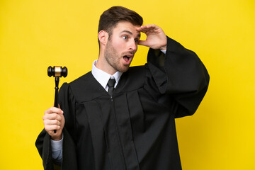 Naklejka premium Judge caucasian man isolated on yellow background doing surprise gesture while looking to the side