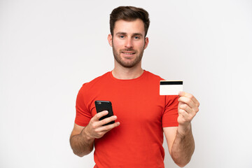 Young caucasian man isolated on white background buying with the mobile with a credit card