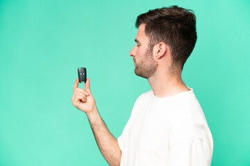 Young caucasian man holding car keys isolated on green background with happy expression