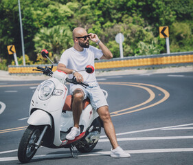 Stylish young man with his motorbike on the road