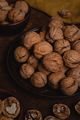 Ceramic plate with dried walnuts and yellow napkin on a wooden table. Top view.