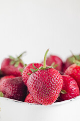 Red strawberries in a white square bowl on a white background..