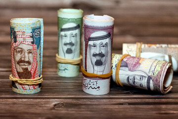 Saudi Arabia money roll riyals banknotes isolated on wooden background, Saudi riyals cash money...