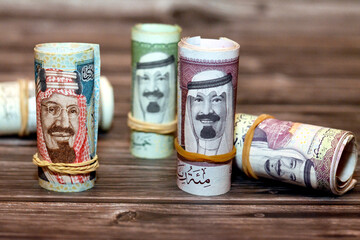 Saudi Arabia money roll riyals banknotes isolated on wooden background, Saudi riyals cash money...