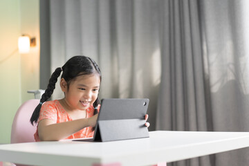 asian child smile learning with touch screen on computer tablet or kid girl student study online...