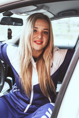 a beautiful young woman in a blue-white sports costume is posing  with white car