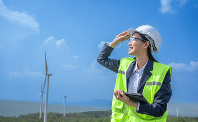 Asian woman Power engineer are working with wind turbines.Electrical engineer female Renewable Energy power plant Sustainability concept.Professional Expert wind power clean energy farm.