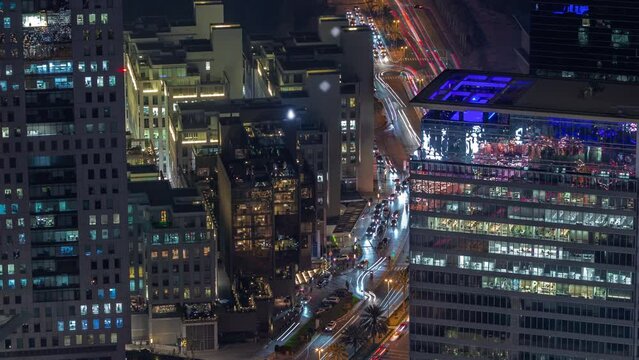 Office skyscrapers with illumination in financial district aerial night timelapse. Top view to hotels and traffic on a road from above