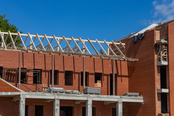 Construction of a large red brick Catholic church. Construction of a peaked roof from wooden beams