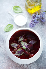 White bowl with borscht or soup made of beetroots and meat, high angle view on a roseate stone background, vertical shot