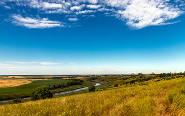 Fototapeta premium Sunny summer landscape with golden wheat fields, river and blue sky.