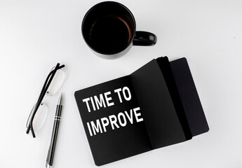 Naklejka premium TIME TO IMPROVE written text in small black notebook with coffee , pen and glasess on white background. Black-white style