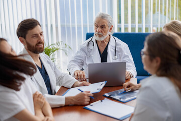 Group of doctors sitting at meeting table in conference room during medical seminar
