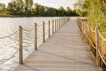 Long Wooden bridge over lake. Beautiful sunrise over lake pier. Planked footway on the river or lake