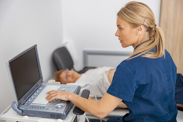Fototapeta premium Focused doctor ultrasound examine senior patient abdomen at hospital. Prenatal diagnosis center