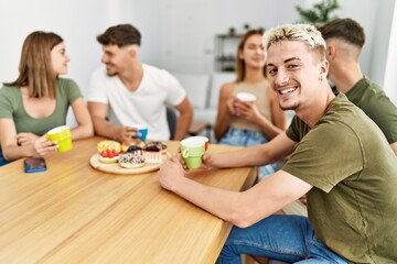 Group of young friends smiling happy having breakfast sitting on the table at home.