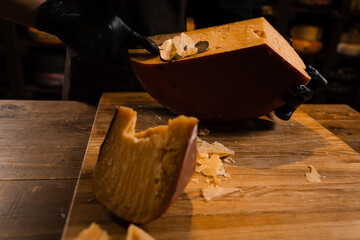 Cheese sommelier slice limited gouda cheese with slicer. Slicing cheese in store. Snack tasty piece of cheese for appetizer.