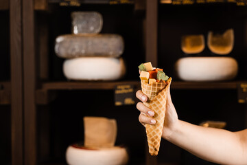 Creative photo of mix of cheeses in waffle cup. Mix of young Gouda, young goat, lavander cheese and green and red pesto cheeses in waffle cup. Creative idea for advertising a cheese shop.
