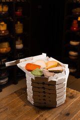 Mix of young Gouda, young goat, lavander cheese and green and red pesto cheeses in the cardboard box. Creative idea for advertising a cheese shop.