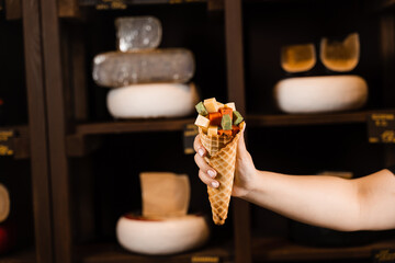Creative photo of mix of cheeses in waffle cup. Mix of young Gouda, young goat, lavander cheese and green and red pesto cheeses in waffle cup. Creative idea for advertising a cheese shop.