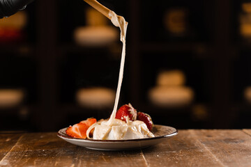 Eating hot baked brie cheese with grissini sticks. Stretching melted Camembert cheese Italian traditional delicacy.