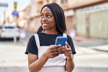 Young african american woman smiling confident using smartphone at street