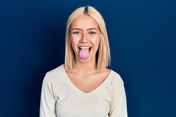 Beautiful blonde woman wearing casual sweater sticking tongue out happy with funny expression. emotion concept. © Krakenimages.com