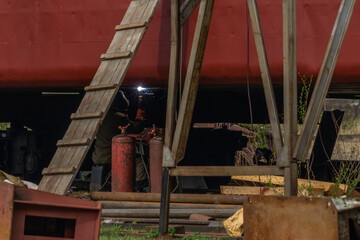 Fototapeta na wymiar Masked welder welds the bottom of the ship