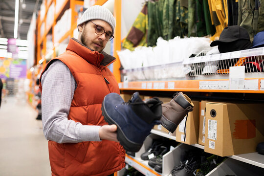 a man in a hardware store chooses safety shoes for construction work