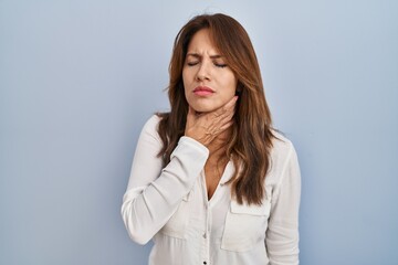 Hispanic woman standing over isolated background touching painful neck, sore throat for flu, clod and infection