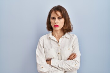 Young beautiful woman standing casual over blue background skeptic and nervous, disapproving...