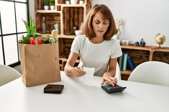 Young caucasian woman doing accounting of groceries purchase at home