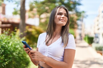 Young woman smiling confident using smartphone at park