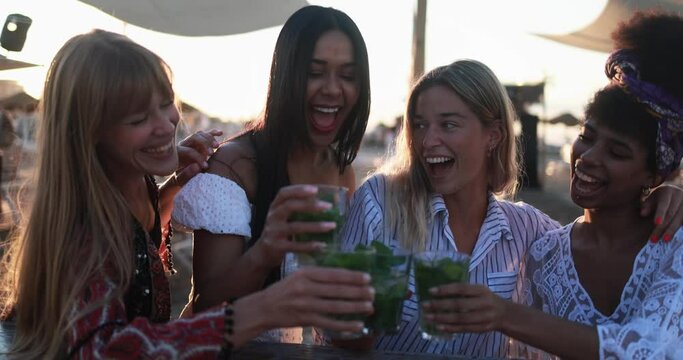 Happy multiracial girls having fun cheering with mojitos at beach party outdoor