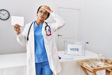 Young african american doctor woman voting holding envelope stressed and frustrated with hand on...