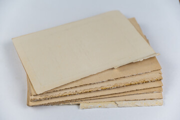 An old tattered book against a neutral background. Brown pages. Softcover. Torn text blocks. Selective focus.