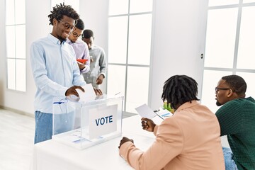 Group of young african american voter people putting vote in ballot standing at electoral center.