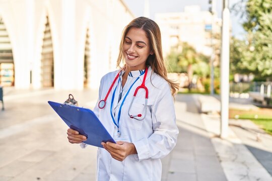 Young blonde woman wearing doctor uniform holding checklist at hospital