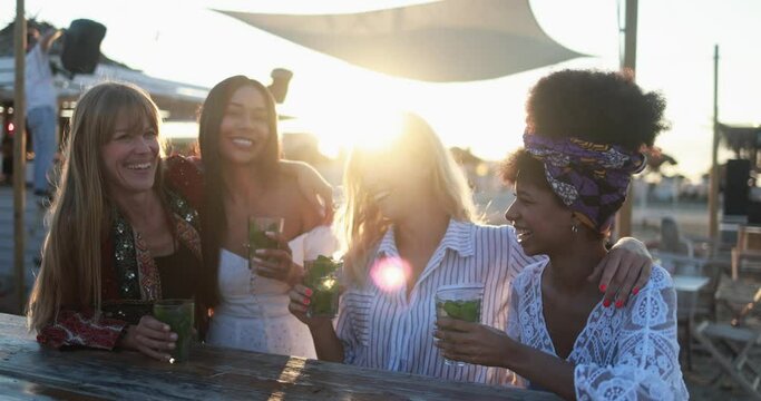 Happy multiracial girls having fun drinking mojitos at beach party outdoor