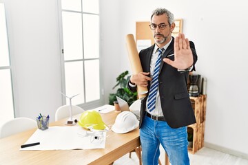 Middle age hispanic business man holding paper blueprints doing stop sing with palm of the hand. warning expression with negative and serious gesture on the face.