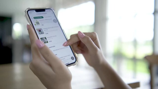 Bangkok, Thailand - Nov 09, 2021: woman in with mobile phone in hands chooses fast food in an online store to place an orders at home. Orders food using online delivery.
