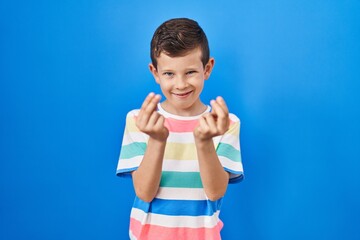 Young caucasian kid standing over blue background doing money gesture with hands, asking for salary...