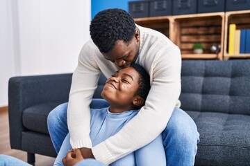 Fototapeta premium Man and woman couple hugging each other sitting on sofa at home