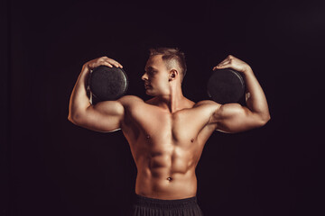Fototapeta na wymiar Power, strength, excellent body, bodybuilding, sports concept. Young handsome muscular fit man demonstrating perfect body and hold circles of cheese in black wax