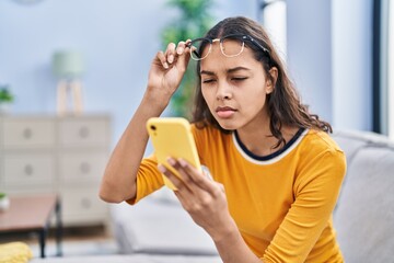 Young african american woman using smartphone sitting on sofa at home