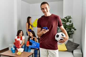 Group of young friends watching and supporting soccer match at home.