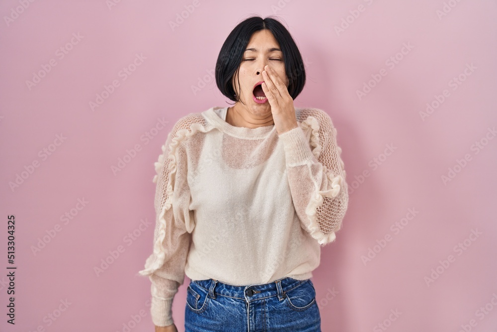 Poster Young asian woman standing over pink background bored yawning tired covering mouth with hand. restless and sleepiness.