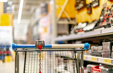A shopping cart by a store shelf in a hardware store