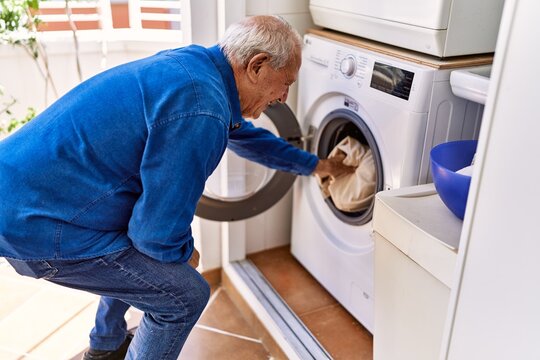 Senior caucasian man smiling happy doing laundry at the terrace.