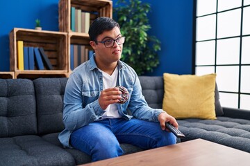 Down syndrome man watching tv eating doughnut at home